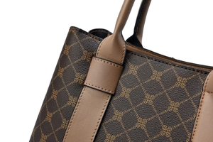 Detail of classic tote bag showing dark brown logo canvas and premium leather stitching