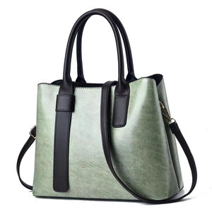 Classic sage green leather tote bag with brown handles and adjustable crossbody strap