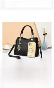 Détail d'un sac à main noir texturé avec ferrures dorées et pendentif en forme de feuille