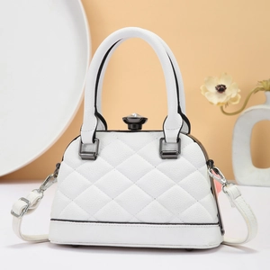 Quilted white shell handbag with top handle and crystal buckle on a warm artistic background