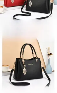 Détail du sac à main en cuir grainé avec pendentif feuille dorée et logo chic