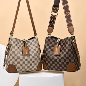 Detail of vintage checkerboard bucket bags with wide adjustable straps on minimalist podium