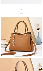 Détail de la texture cuir marron motif litchi et du pendentif feuille dorée du sac