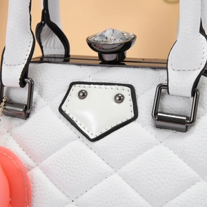 Detail of white quilted leather handbag featuring a large diamond-cut crystal metal clasp
