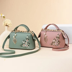 Detail of floral embroidery and pearl leaf pendant on vintage faux leather handbags