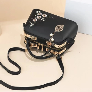 Detailed view of floral embroidery and multi-layer zippers on a black tote bag