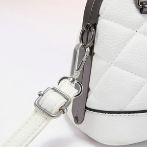 Detail of white quilted leather bag showing dark gray metal frame and silver swivel clasp