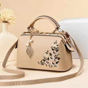 Detailed embroidery of pink flowers and gold leaf pearl pendant on beige tote bag