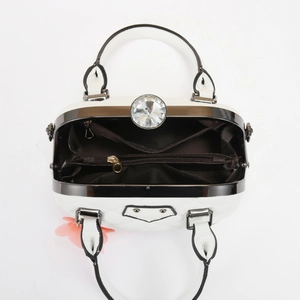 Detail view of white shell bag interior with multiple compartments and diamond clasp