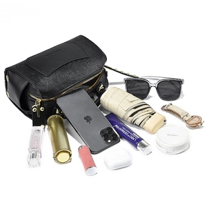 Flat lay of small black handbag showing spacious interior with daily essentials like a phone