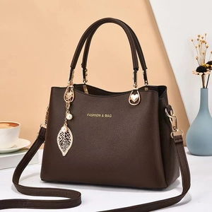 Sac à main en cuir marron foncé avec pendentif feuille dorée et perle sur fond moderne