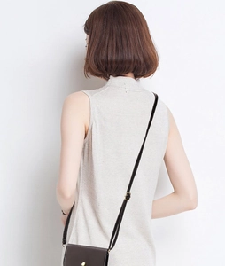 Detail of a minimalist brown leather mini bag paired with a knit vest for a stylish look