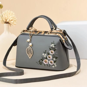 Detail of grey handbag featuring floral embroidery and vintage metal frame closure