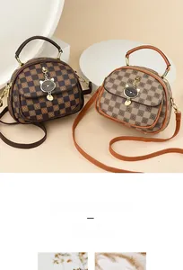 Detail of checkered crossbody bags with metallic cat charms and magnetic flap closures