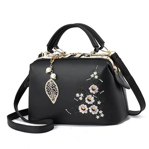 Elegant black doctor bag with floral embroidery, pearl leaf charm, and top handles