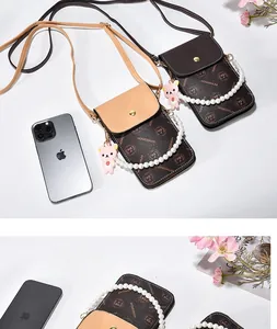 Detail of vintage patterned crossbody phone bags with pearl chain and bear charm
