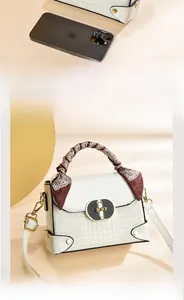 Détail du sac à main blanc motif crocodile avec foulard en soie et boucle dorée