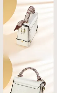 Détail du sac à main blanc motif crocodile avec foulard en soie sur la poignée