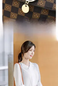Detail of checkered pattern with floral motif and golden pendant on women's handbag
