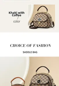 Detail of vintage checkered saddle bag with cat pendant and brown leather handles