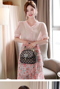 Detail of checkered pattern handbag with silver cat-shaped clasp and dual zippers