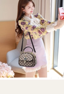 Classic checkered crossbody bag featuring a unique cat-shaped metal clasp on a model