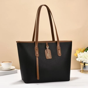 Detail of black lychee-textured tote bag with brown handles and golden hardware accents
