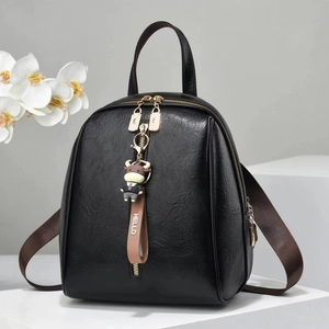 Detail of black pebbled leather backpack with gold zippers and cartoon bull charm