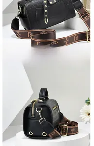 Detail of black Boston bag with golden rivets and patterned brown woven strap