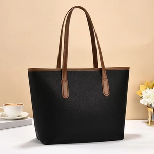 Close-up of litchi texture on black tote bag with brown handles and stitching detail