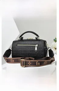Detail of embossed letter pattern on black leather pillow bag with gold hardware