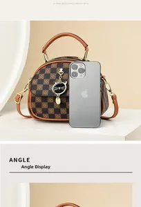Detail view of retro checkered handbag with cat charm and phone for size reference