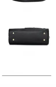 Vue détaillée du sac en cuir noir avec lettres embossées et rivets dorés sur le fond