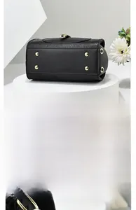 Detail showing the bottom of a black leather handbag with gold anti-wear rivets