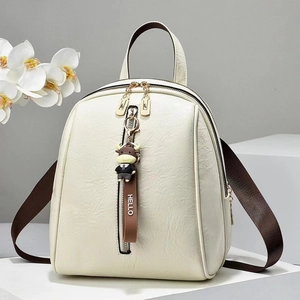 Detail of cream soft leather backpack with lychee texture and cartoon bull charm