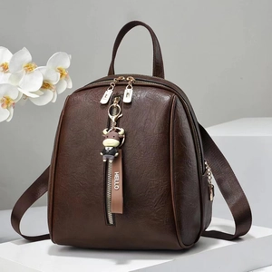 Detail of soft dark brown pebble leather backpack featuring gold zippers and cute charm
