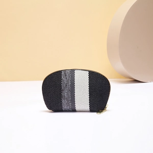 Detail of a semi-circular knitted makeup bag with black, gray and white vertical stripes