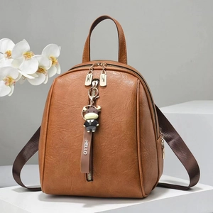 Women brown soft leather backpack with bull charm on minimalist geometric display