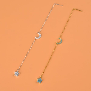 Dettaglio degli orecchini pendenti a luna e stella in argento e oro con zirconi lucidi