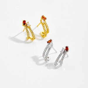 Detail of C-shaped hoop earrings with micro zircons and orange marquise-cut stones