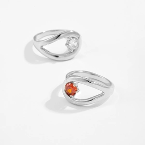 Detailed view of silver openwork rings with round white and orange zircon stones