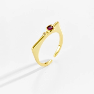 Detail of adjustable gold ring featuring a red gemstone and modern geometric design