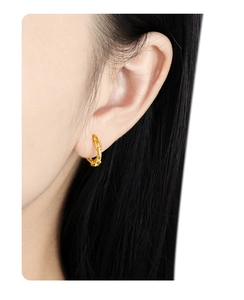Macro side view of a model wearing a gold chain link hoop earring in polished finish