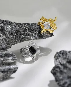 Irregular textured silver rings with zircon stones displayed on a dark natural rock surface