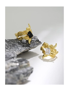 Close-up of irregular textured gold rings with black and clear rectangular zircons