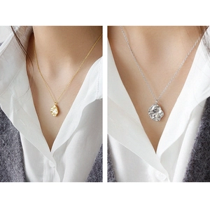 Detalle de collares con colgante de textura de roca irregular en acabados oro y plata