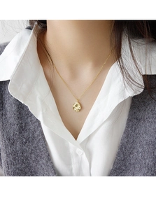 Detalle de un collar dorado con colgante de textura irregular en el cuello de una modelo