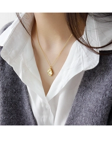 Primer plano de un collar dorado con colgante irregular estilo lava en una modelo