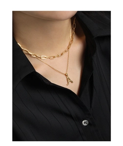 Detail of layered gold S925 sterling silver necklaces with letter A pendant on black shirt