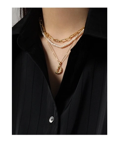 Detailed close-up of a three-layer gold chain necklace with pearls and letter D pendant